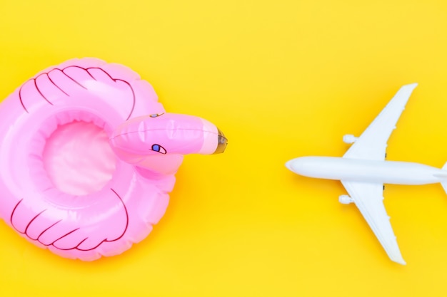 Mínimo plano simples colocar com avião e flamingo inflável isolado em fundo amarelo