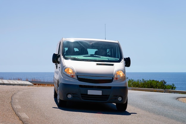 Minivan auf der Straße in Villasimius in Cagliari auf der Insel Sardinien in Italien. Mittelmeer im Hintergrund.