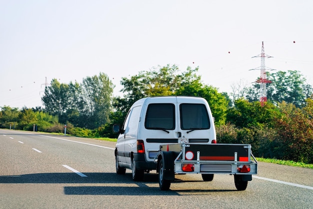 Minivan mit Anhänger auf der Asphaltstraße in Slowenien.