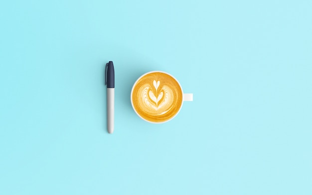 Minmal-Arbeitsplatz mit Lattekaffeetasse und Stift auf blauer Farbe