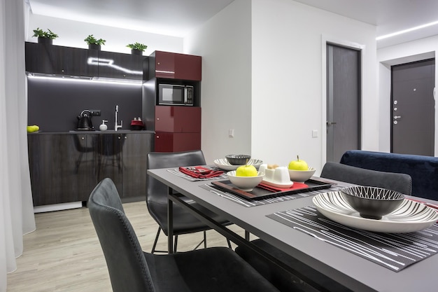 MINSK BIELORRUSIA MARZO 2020 Interior de la moderna cocina de lujo con mesa de invitados en apartamentos estudio de estilo minimalista con color rojo oscuro