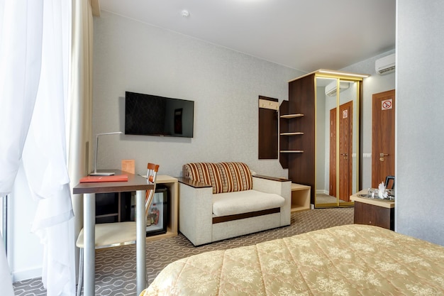 MINSK WEISSRUSSLAND OKTOBER 2020 Einrichtung des modernen Gästezimmers in Studio-Apartments oder Hotels mit Sofatisch, Sesseln, rotem Teppich und LED-Licht