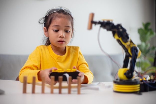 MINT-Bildungskonzept Asiatische Schüler lernen zu Hause, indem sie Roboterarme in MINT-Mathematik, Ingenieurwesen, Wissenschaftstechnologie, Computercode in Robotik für Kinderkonzepte programmieren