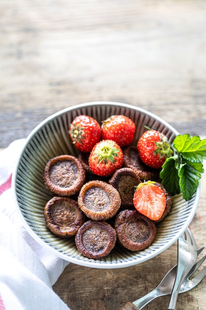 Minúsculo cereal de panqueca de chocolate em uma tigela com morangos