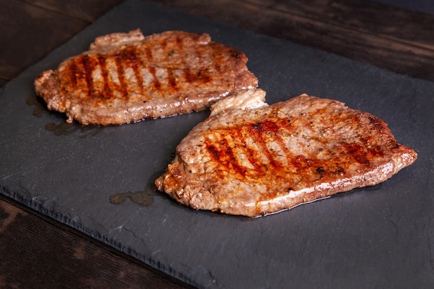 Minuto bistec a la parrilla de carne de vacuno de mármol en un tablero de pizarra de piedra de cerca