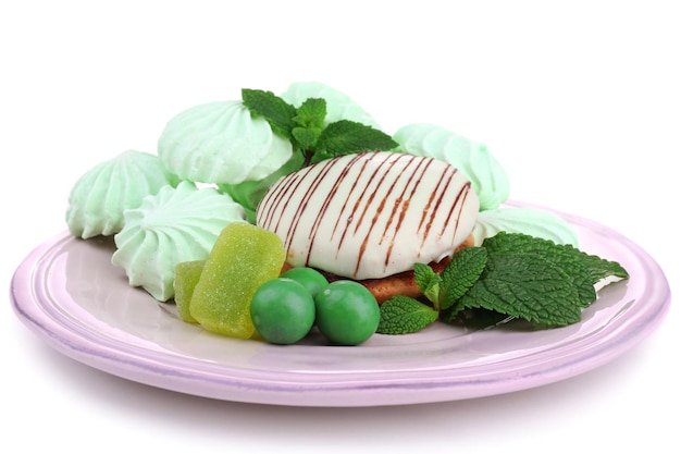 Minzfarbene Meringues, Minzgeleebonbons und leckerer Kuchen auf Teller isoliert auf Weiß