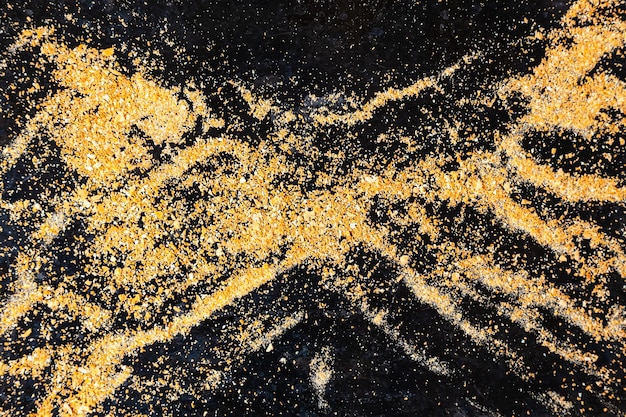 Miolo de pão pequeno em preto Pó de ouro em um fundo preto Pequenas partículas de rocha de ouro em preto
