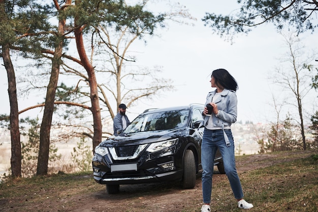 Mira atrás al novio. Pareja ha llegado al bosque en su nuevo coche negro