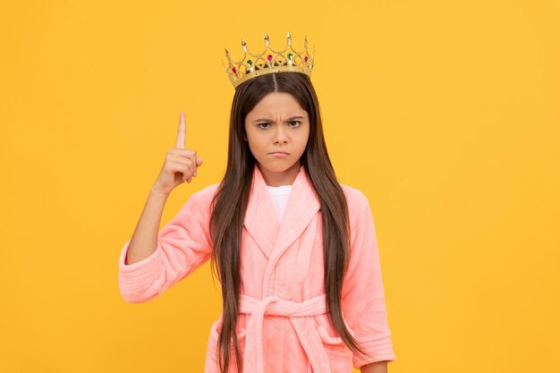 Mira esto. niño egoísta usa diadema. niño reina en ropa de dormir acogedora. cómodo albornoz de casa. egoísmo y egoísmo. chica egocéntrica en el dedo levantado de la corona. felicidad infantil. princesa belleza