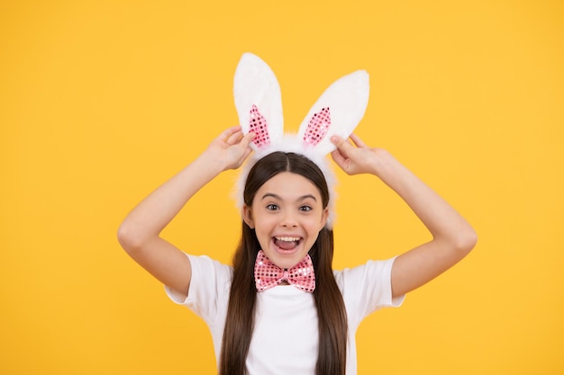 Mira a ese niño gracioso con orejas de conejo, una adolescente sonriente con pajarita, la caza del conejito comienza a divertirse, listo para la fiesta, la infancia feliz, el conejito alegre, felices vacaciones de Pascua.