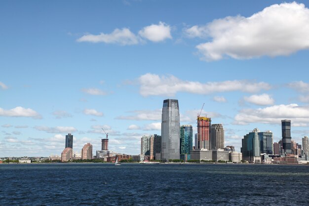 Mira en el velero de crucero en los edificios del puerto de Nueva York de la isla de Manhattan en el fondo