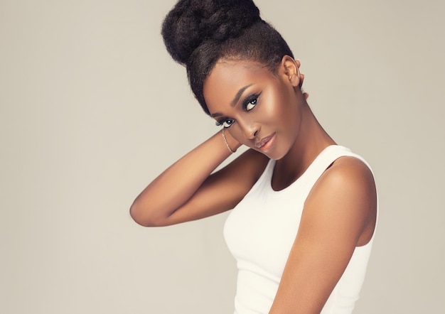 Mirada juguetona y sonrisa tierna en la cara del joven y atractivo modelo de piel marrón afro peinado