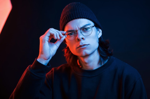 Mirada segura. Foto de estudio en estudio oscuro con luz de neón. Retrato de hombre serio.