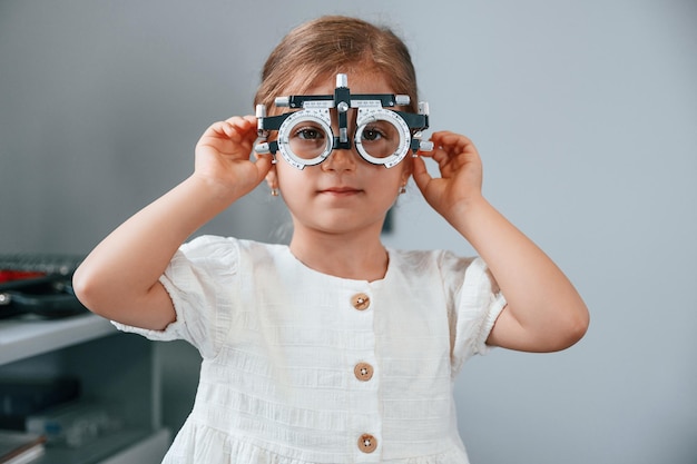 Mirando hacia adelante con un dispositivo especial en los ojos Niña revisando su visión usando un dispositivo especial de optometrista