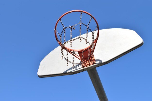 Mirando hacia arriba a un aro de baloncesto contra un cielo azul claro