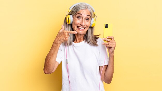 Mirando emocionado y sorprendido apuntando hacia un lado y hacia arriba para copiar el espacio con auriculares