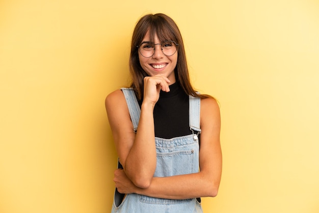 Mirando feliz y sonriendo con la mano en la barbilla preguntándose o haciendo una pregunta comparando opciones