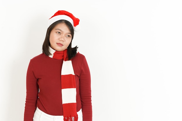 Mirando a un lado de la hermosa mujer asiática con cuello alto rojo y gorro de Papá Noel aislado en blanco