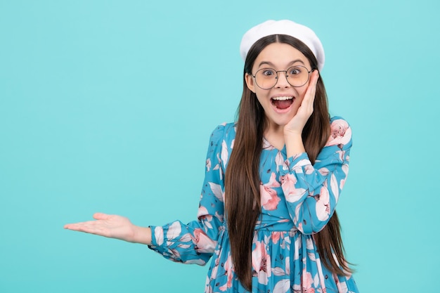 Mire el anuncio El niño adolescente señala a un lado muestra un espacio en blanco para la presentación de la idea promocional de texto posa Emocionado adolescente sorprendido y alegre emociones