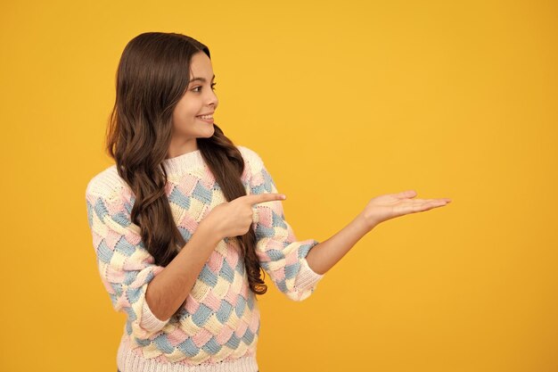 Mire el anuncio Los puntos del niño adolescente a un lado muestran el espacio en blanco para la presentación de la idea de promoción de texto posa contra el fondo amarillo