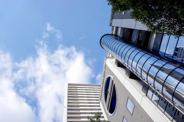 Mire para arriba la vista y la cosecha del edificio de oficinas en fondo brillante del cielo azul. con espacio para textos