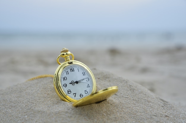 Mire la bolsa vieja en la playa con el concepto tradicional de tiempo que la gente espera