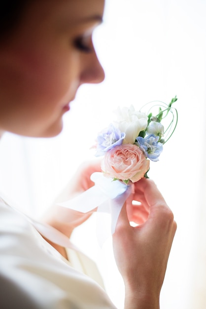 Mire sobre el hombro de la novia en el boutonniere tierno en sus brazos