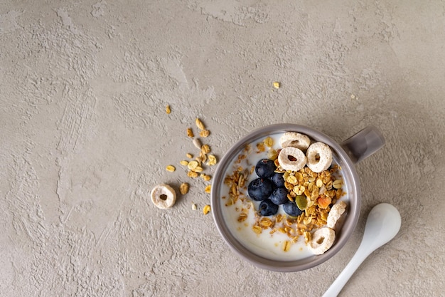 Mirtilos de granola de iogurte em um copo no espaço de cópia de gesso cinza