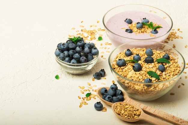 Mirtilos de iogurte de granola em tigelas em fundo cinza Conceito de menu de café da manhã saudável