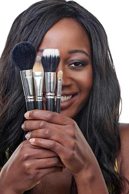 Mis herramientas de belleza Foto de estudio de una mujer joven sosteniendo un pincel de maquillaje aislado en blanco