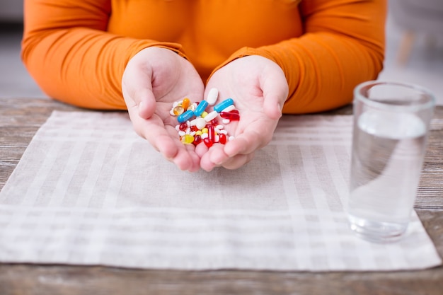 Mis pastillas. Mujer gorda sentada en la mesa y sosteniendo pequeñas píldoras de colores