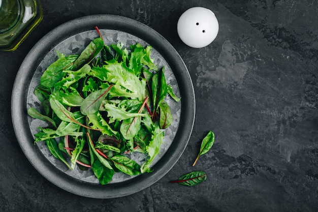 Mischen Sie frische grüne Salatblätter für Salat auf einem Draufsicht-Kopienraum des dunklen Steinhintergrundes