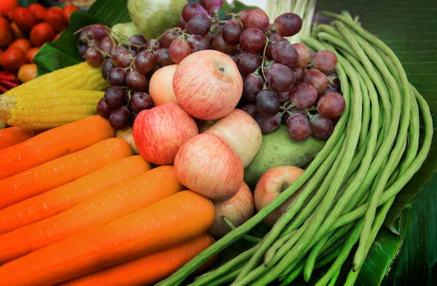 Mischen Sie Obst und Gemüse auf grünem Bananenblatt in Lebensmitteln aus dem Landwirtschaftskonzept für Veganer, darunter Apfelkarotten, Mais, Trauben, Guava und lange Bohne