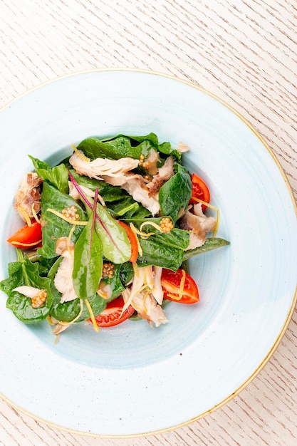 Mischen Sie Salat mit Huhn und Tomaten auf hellem Hintergrund