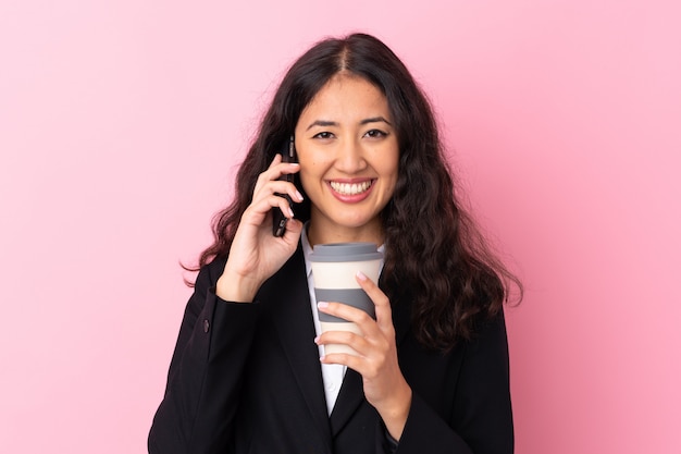 MischrasseGeschäftsfrau, die Kaffee hält, um mit Mobile wegzunehmen und zu sprechen