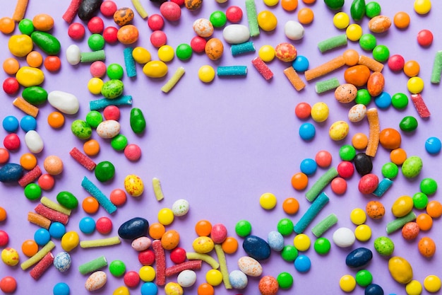 Mischung aus farbenfrohen Süßigkeiten auf farbigem Hintergrund Flach gelegener Top-View-Rahmen aus farbigen schokoladenbeschichteten Süßigkeiten