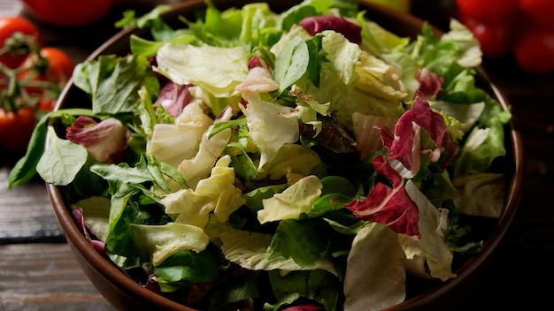 Foto mischung aus frischem grünem salat in einem teller auf dem tisch mit gemüse und gewürzen.