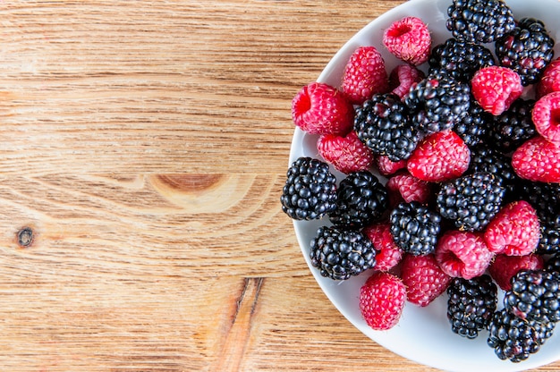 Mischung aus frischen Beeren auf rustikalem Holzhintergrund