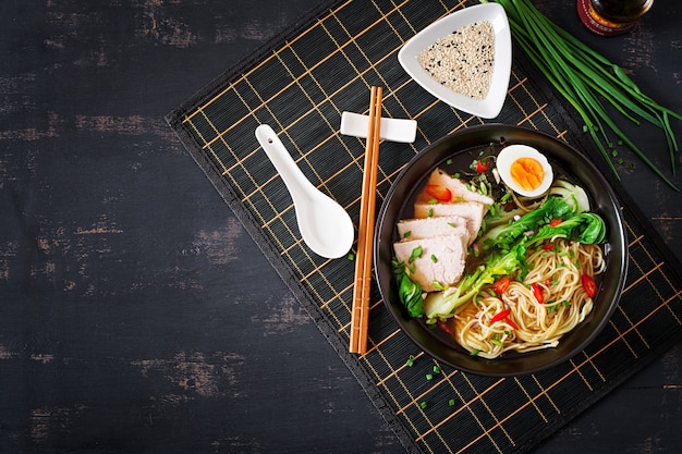 Miso macarrão com ovo, carne de porco e pak choi repolho na tigela na mesa escura