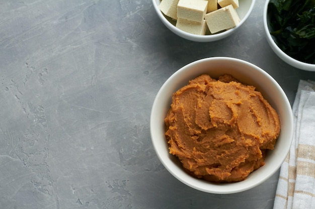 Misopaste Shiro Miso in einer Schüssel auf grauem Hintergrund für Misosuppe mit Tofu Wakame Algen