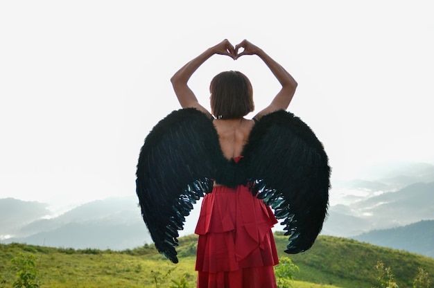 Foto misteriosa dama vestida de rojo ángel del cielo mensajero de la muerte con grandes alas negras