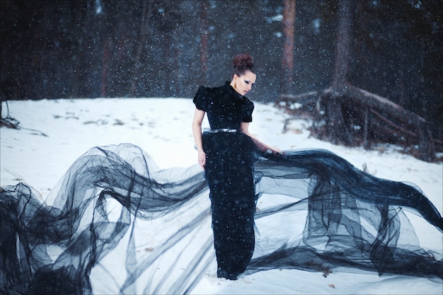 Misterioso retrato artístico de una bella morena con un vestido largo negro de moda