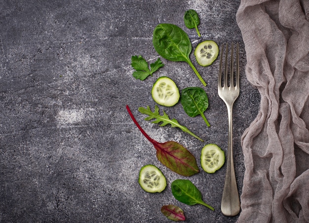 Mistura cortada do pepino e da salada. Fundo verde dos vegetais, conceito saudável do alimento. Vista do topo