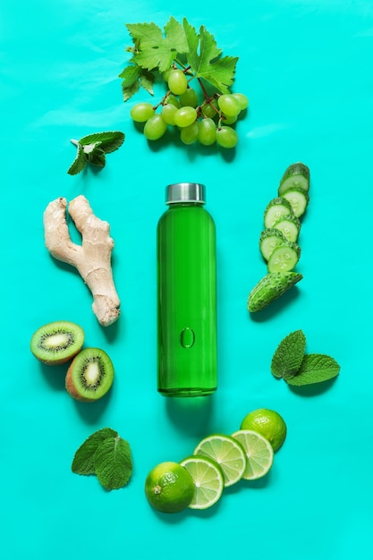 Mistura de bebida imunoestimulante incolor em uma garrafa de vidro transparente e ingredientes frescos frutas e legumes na cor verde sobre fundo verde