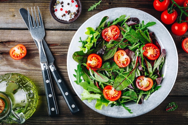 Mistura de folhas de salada verde fresca com beterraba de espinafre alface rúcula e tomate em fundo rústico de madeira Vista superior