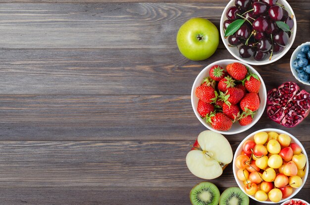 Mistura de frutas, nozes e frutas frescas. A alimentação saudável contém muitas vitaminas e oligoelementos úteis. Fundo de madeira marrom. Copie o espaço.