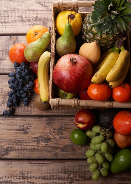 Mistura de frutas tropicais exóticas coloridas e suculentas frescas em uma cesta na vista superior do plano de fundo de madeira