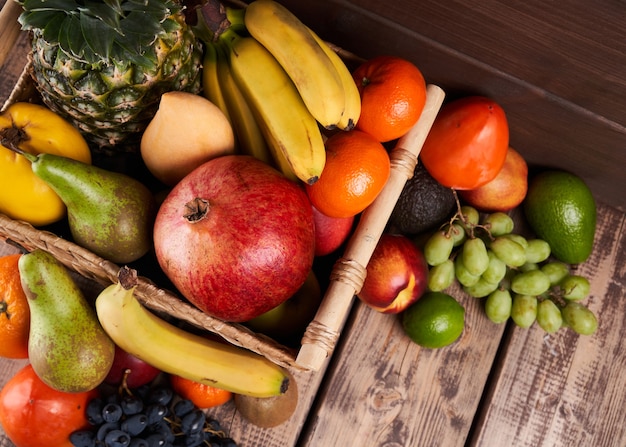 Mistura de frutas tropicais exóticas coloridas e suculentas frescas em uma cesta na vista superior do plano de fundo de madeira