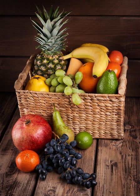 Foto mistura de frutas tropicais exóticas coloridas suculentas frescas em uma cesta com fundo de madeira