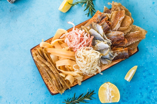 Mistura de frutos do mar secos com lula, atum, bacalhau, minke amarelo na vista superior da placa. filé de peixe curado desidratado como lanche de cerveja